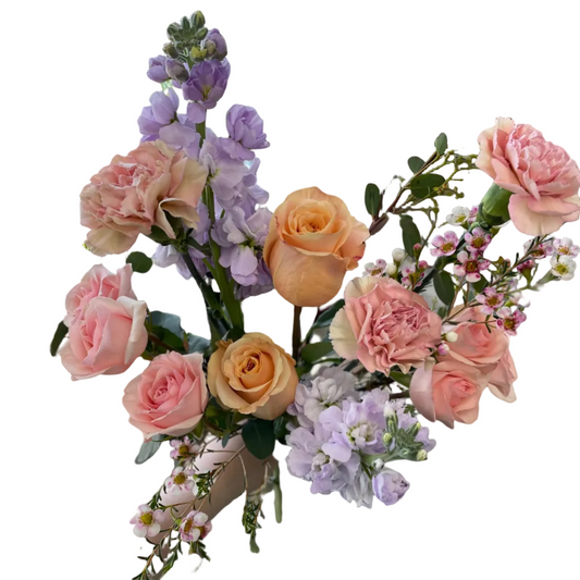 Bouquet of flowers held by a person in an indoor setting with plants in the background.